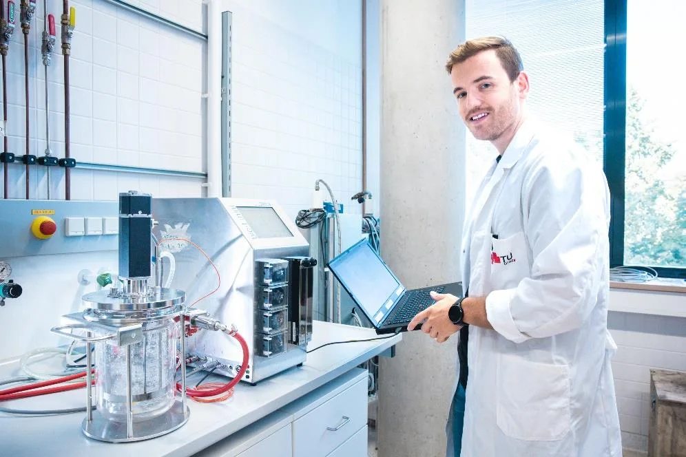 SimVantage engineer working with a laptop at a lab-scale bioreactor